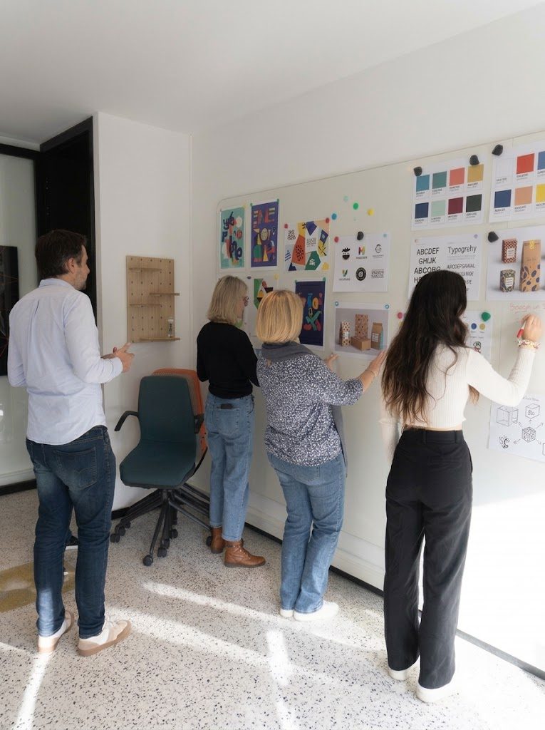 L'équipe Printvallée en séance de travail devant un mur de maquettes et de créations